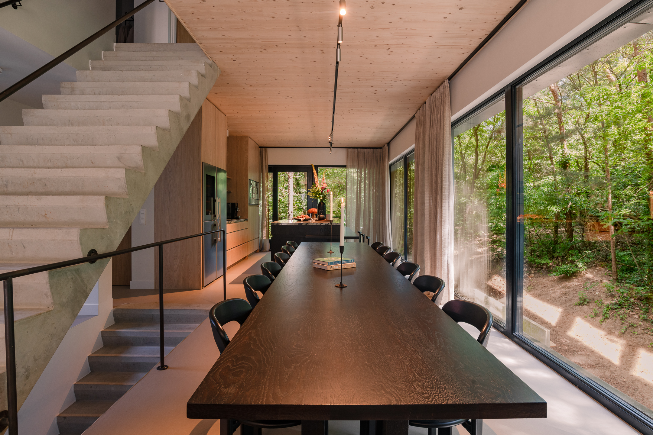 The Living met professionele keuken, lange tafel en uitzicht op het bos
